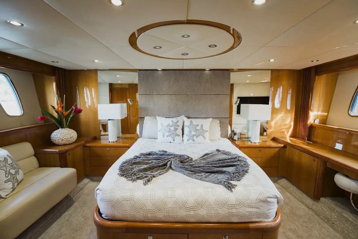 Luxurious yacht bedroom with double bed, starfish pillows, and wood paneling.