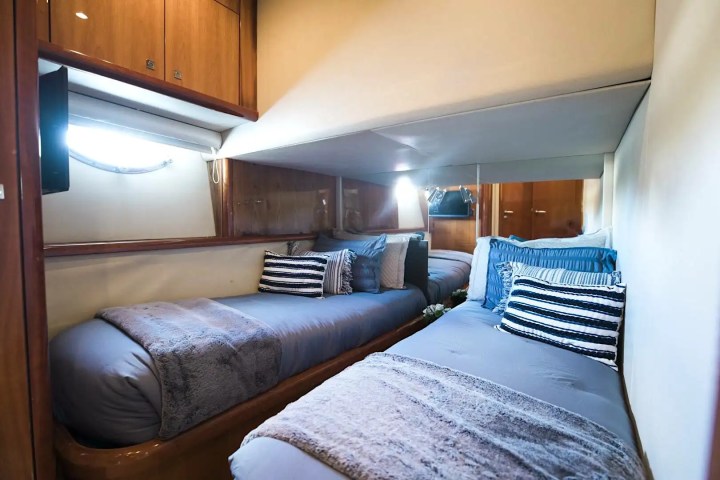Cozy cabin with two beds, striped pillows, and wooden accents inside a yacht.