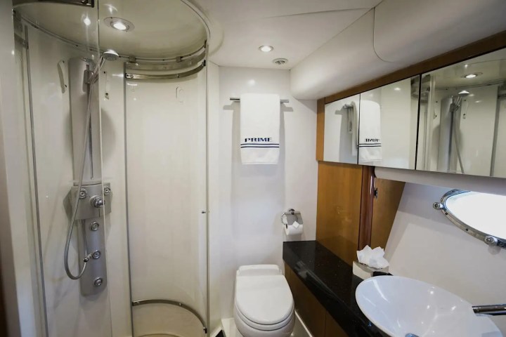Compact bathroom with corner shower, toilet, sink, and mirror cabinet.
