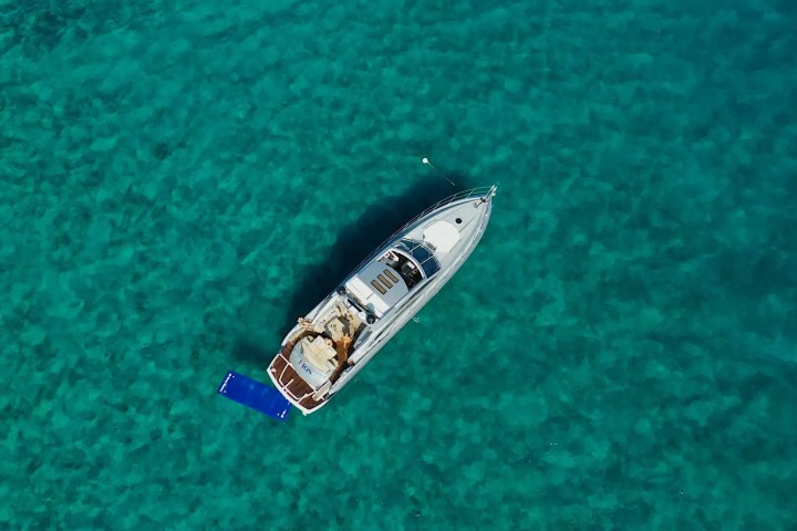 Aerial view of a boat on clear turquoise water with a blue float beside it.