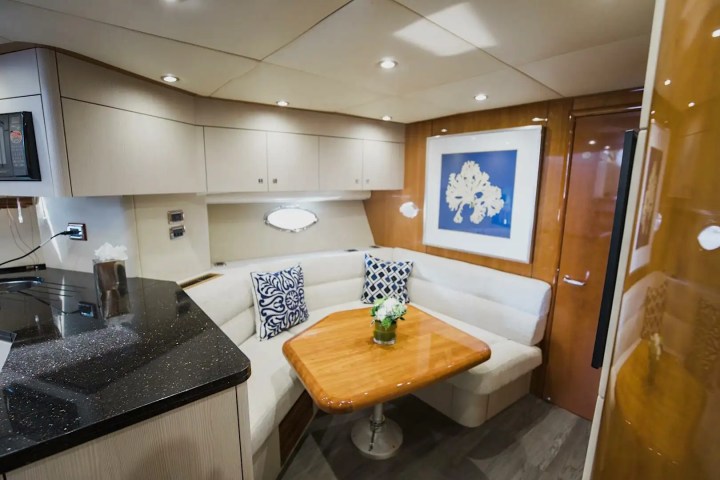 Luxury yacht interior with cushioned seating, wood table, decorative pillows, and wall art.
