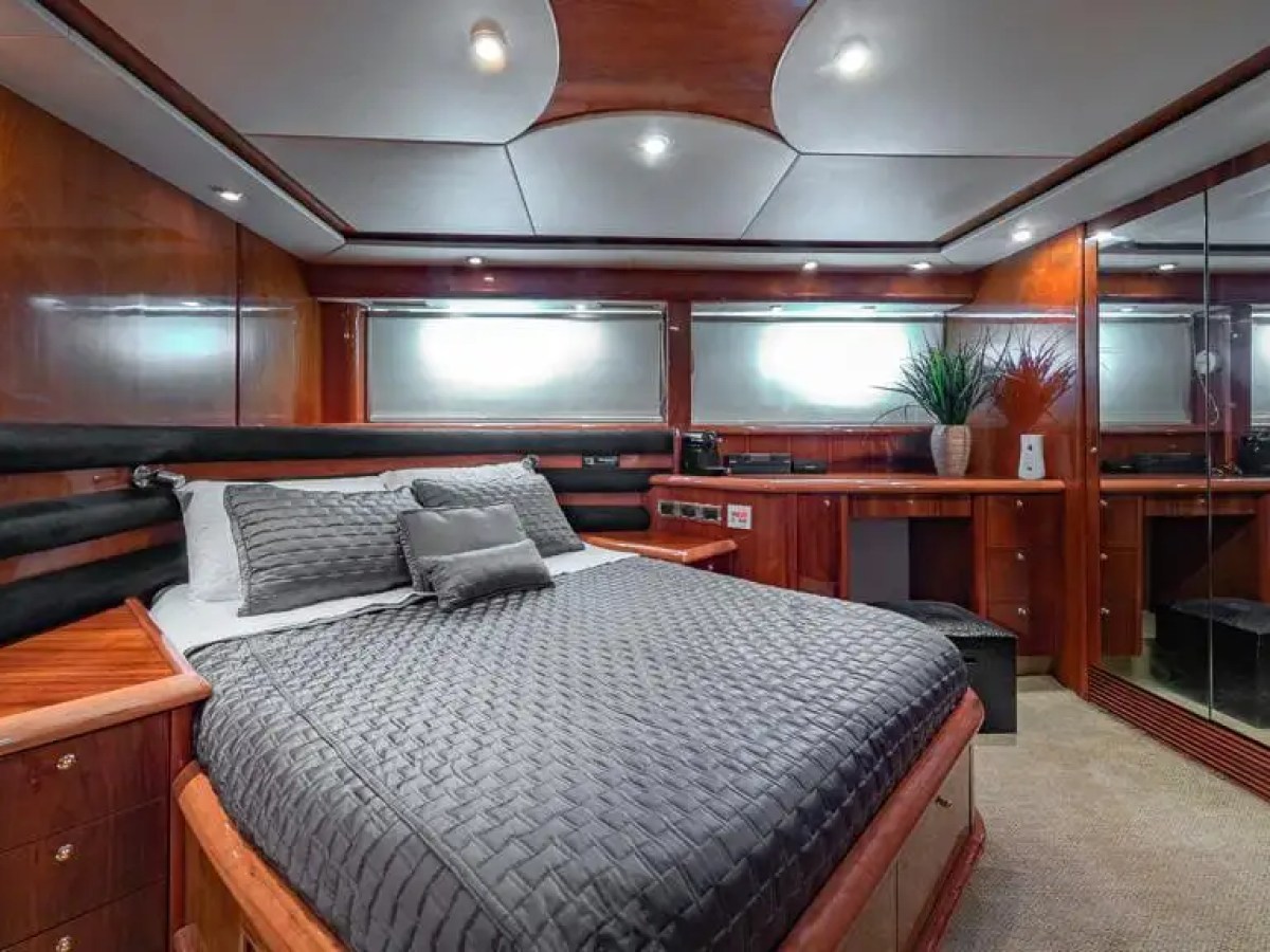 Luxurious yacht bedroom with wooden panels, grey bedding, and a mirrored wall.
