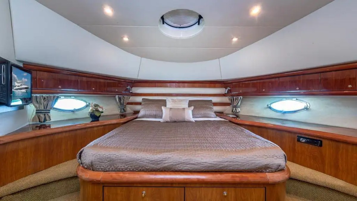 Luxurious cabin bedroom with a large bed, porthole windows, and wooden cabinetry on a yacht.