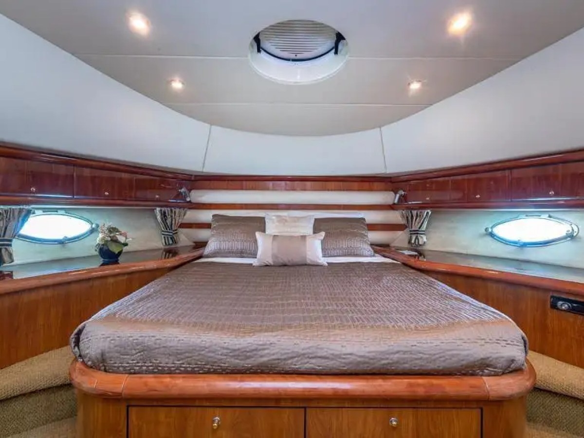 Luxurious cabin bedroom with a large bed, porthole windows, and wooden cabinetry on a yacht.