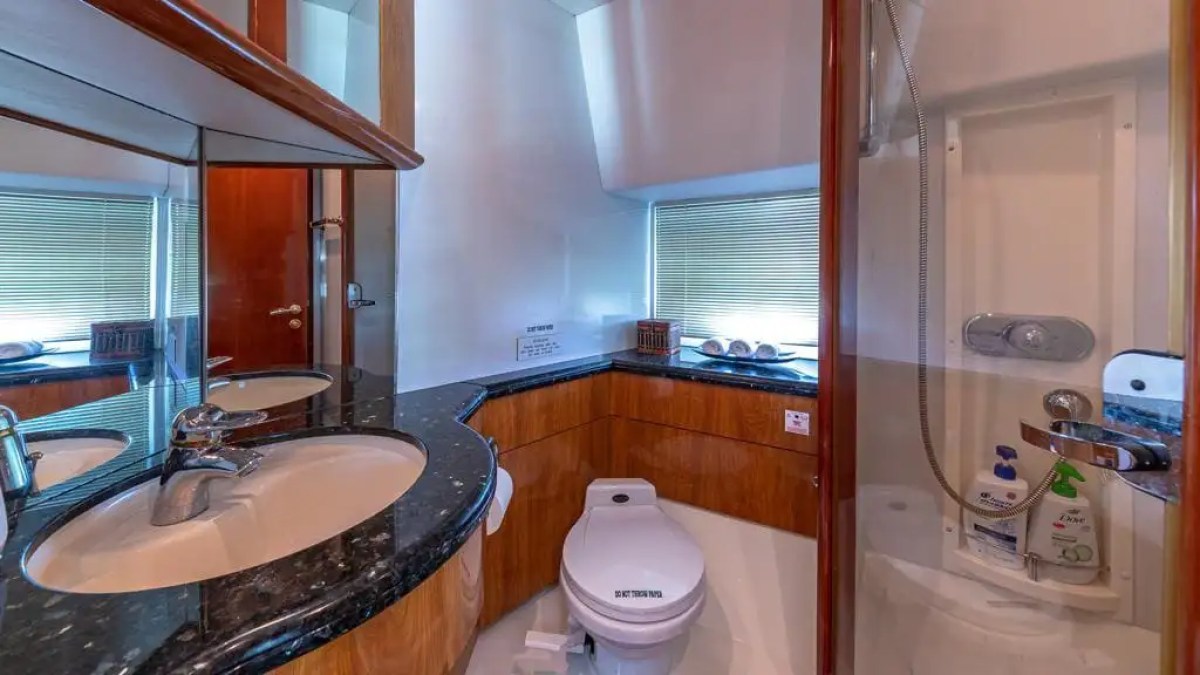 Compact bathroom with sink, toilet, and shower cabin, accented with wood and marble surfaces.