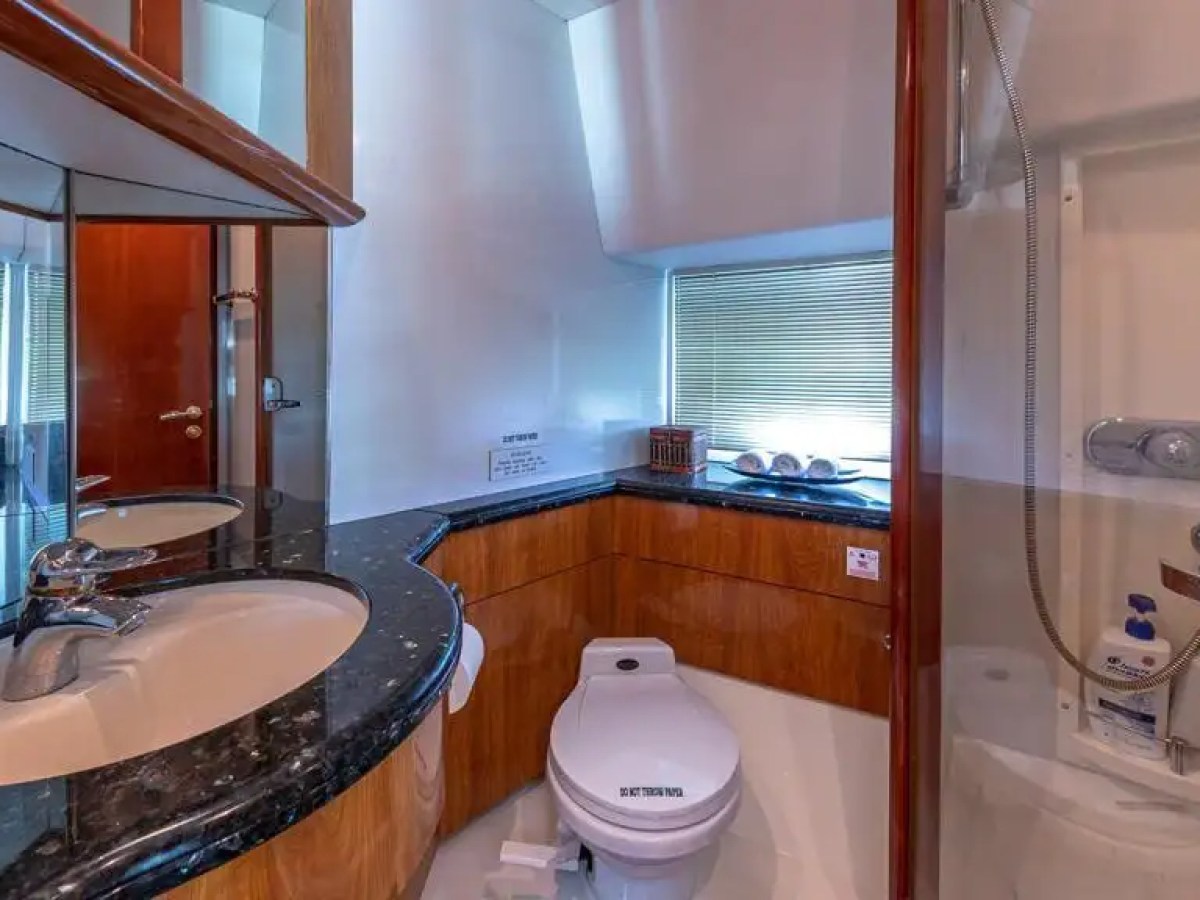Compact bathroom with sink, toilet, and shower cabin, accented with wood and marble surfaces.
