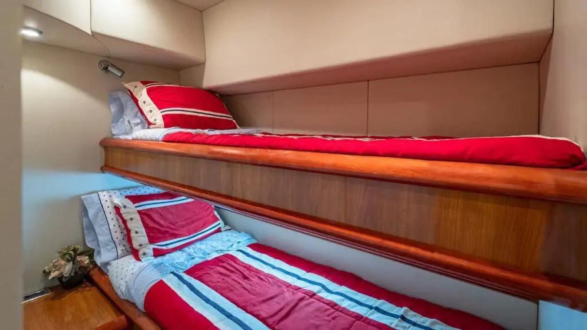 Interior cabin with two wooden bunk beds and red-striped bedding.