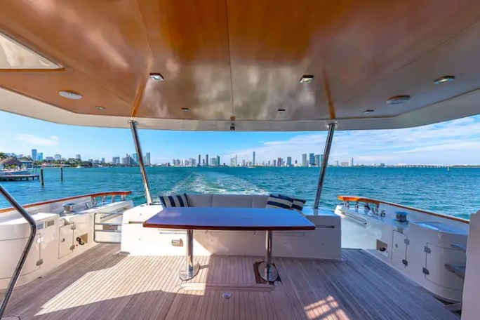 View from yacht deck with table, overlooking city skyline across blue water under clear sky.