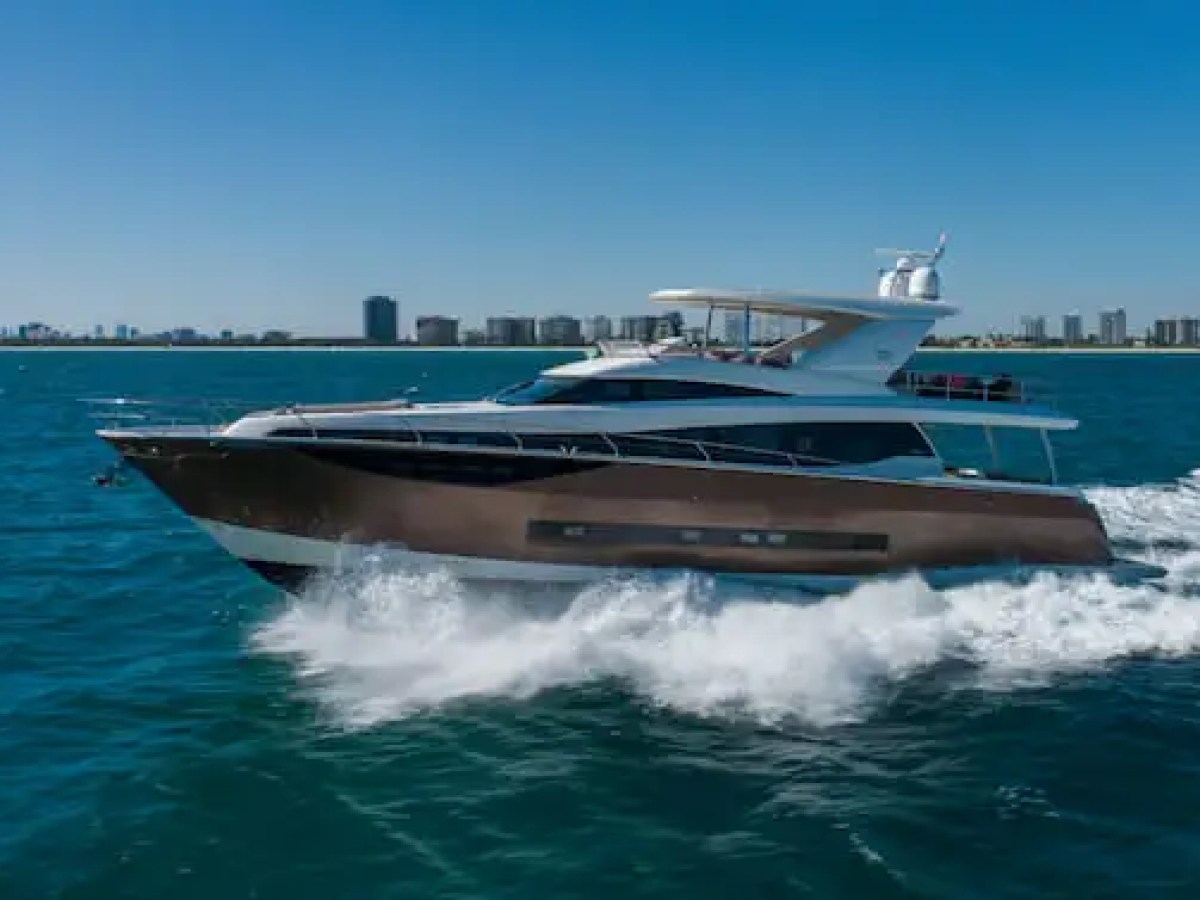 Luxurious cabin cruiser yacht gliding on open sea with city skyline in background.