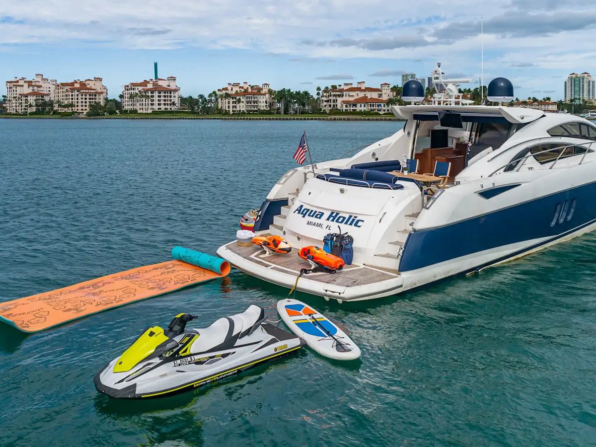 75 Sunseeker Yacht Charter anchored in Nassau Harbor with jet ski, paddleboard, floating water mat, swim platform, and Miami-style luxury cruising amenities visible on calm waterfront