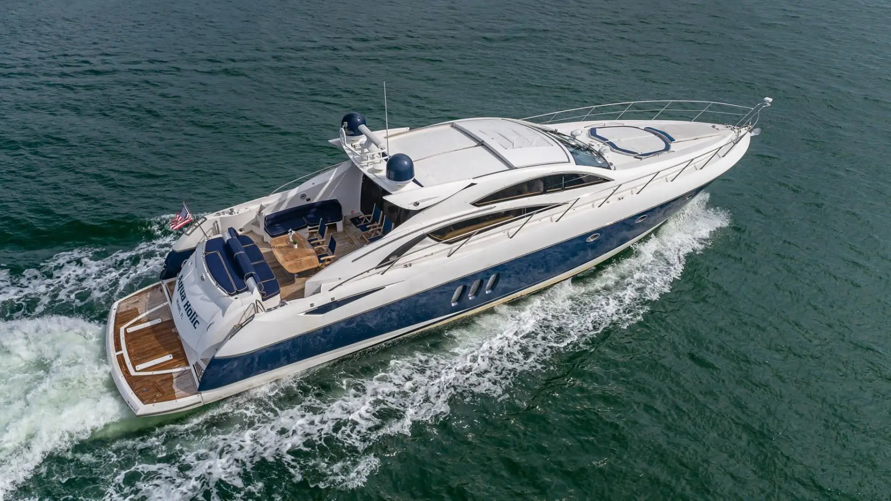 Luxury yacht cruising on open water, viewed from above with waves at the stern.