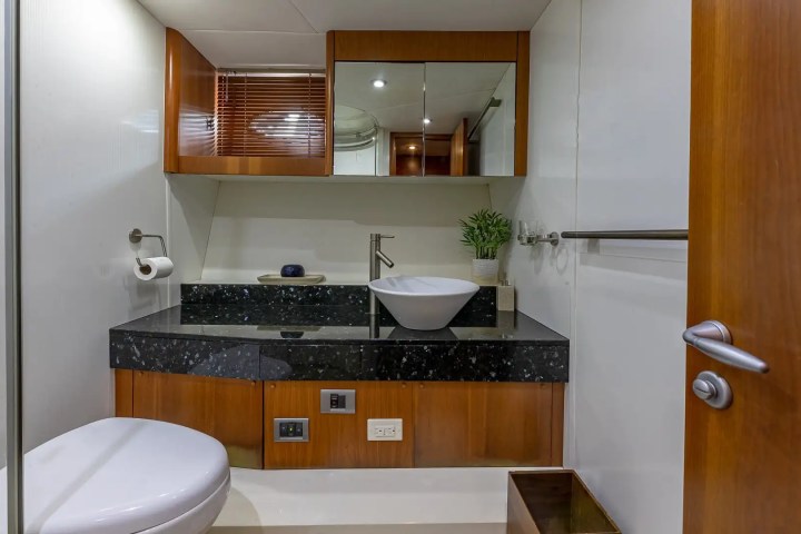 Modern yacht bathroom with sink, toilet, mirror, and wooden accents.