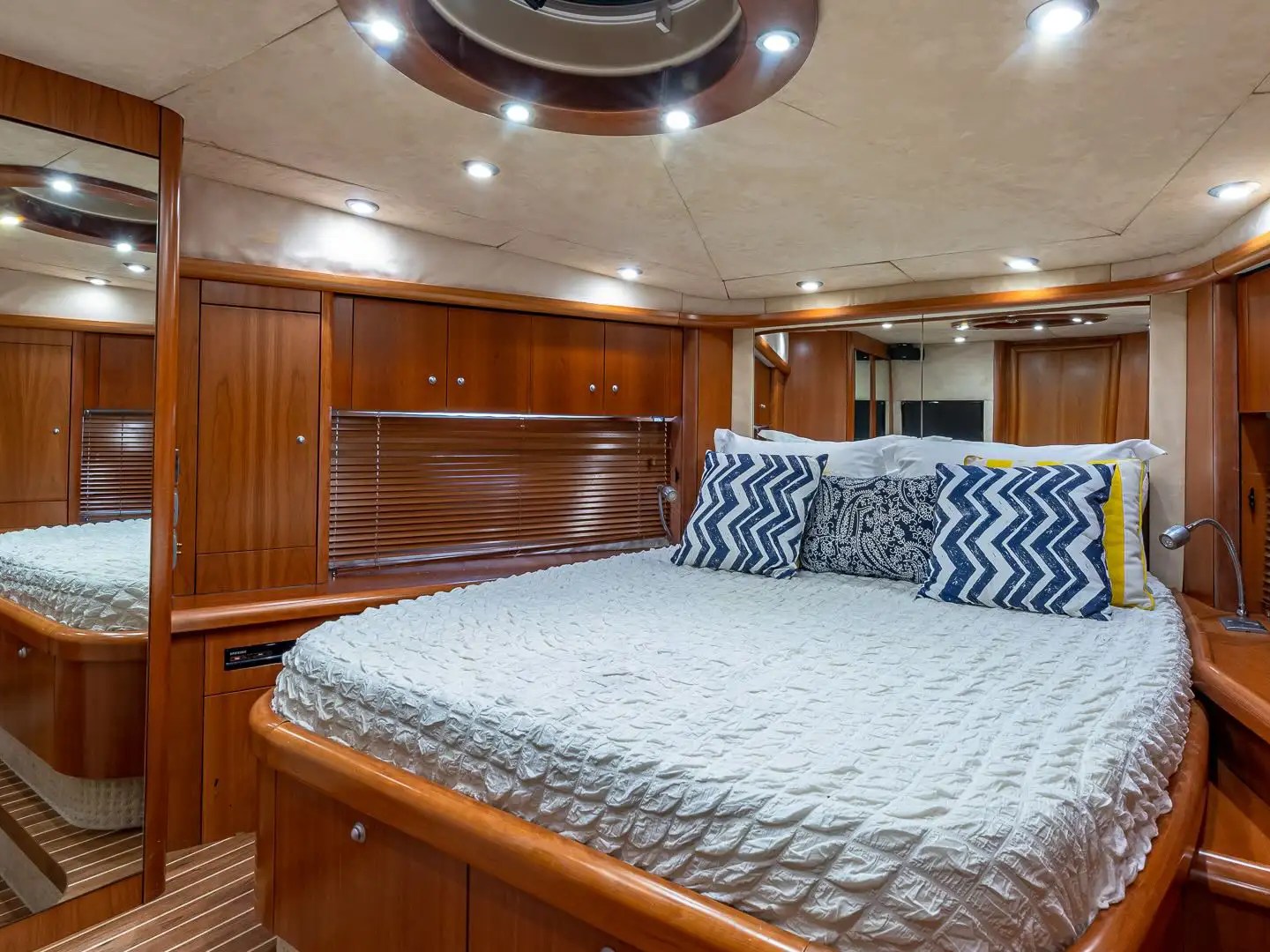 Luxurious boat cabin with a bed, wooden paneling, and decorative pillows.