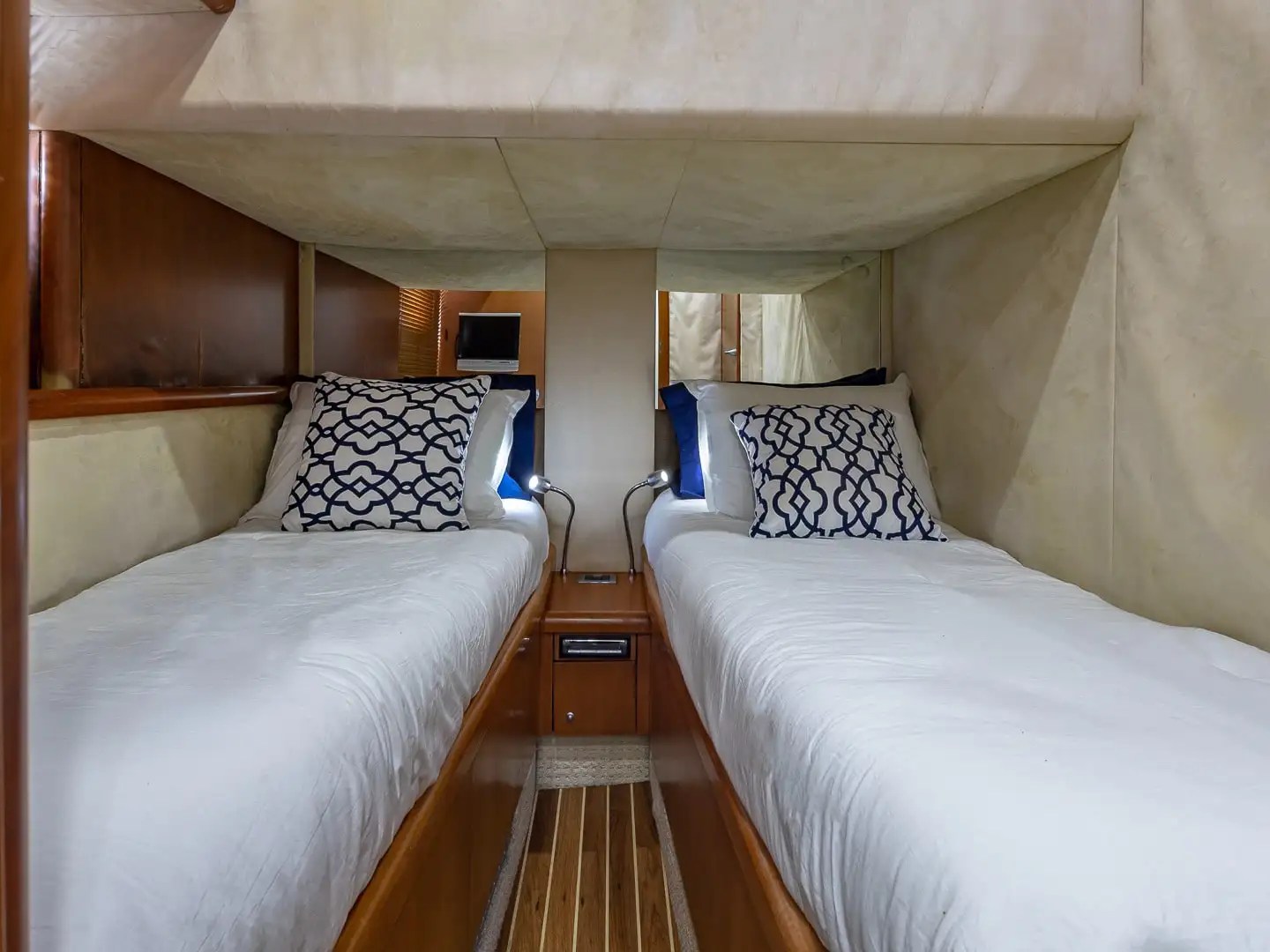 Interior with two twin beds, white sheets, and patterned pillows in a cozy wooden room.
