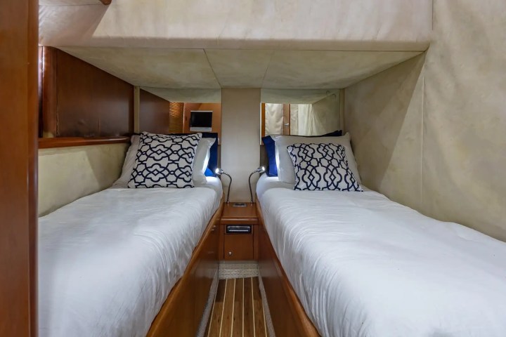 Interior with two twin beds, white sheets, and patterned pillows in a cozy wooden room.
