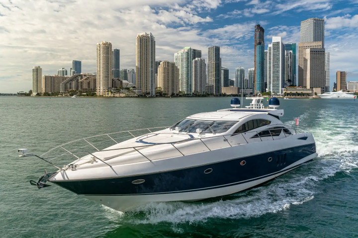 Luxury yacht sailing near a city skyline on a sunny day.
