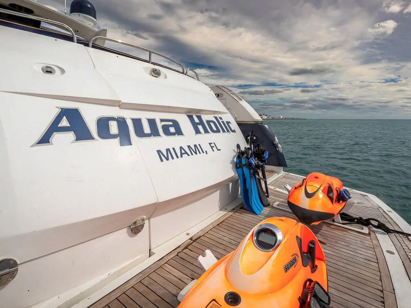 Rear view of a yacht in open water with two orange sea scooters on deck.