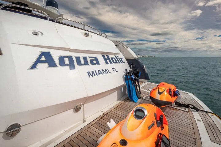 Rear view of a yacht in open water with two orange sea scooters on deck.