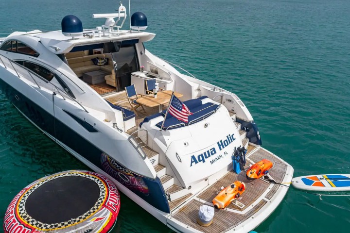 Luxury yacht 'Aqua Holic' with water toys and American flag in blue ocean.