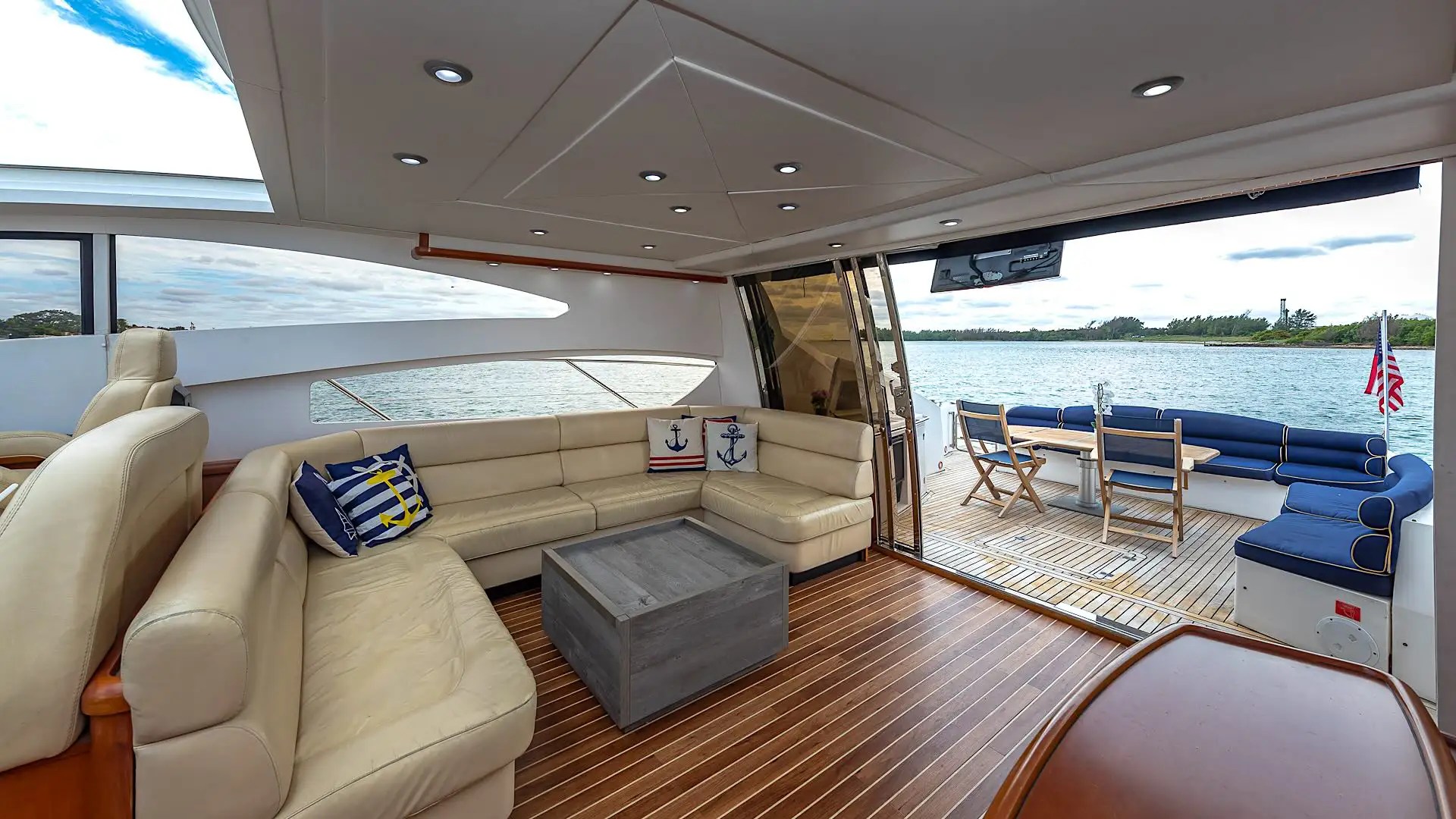 Luxurious yacht interior with leather seating and outdoor deck view over water.