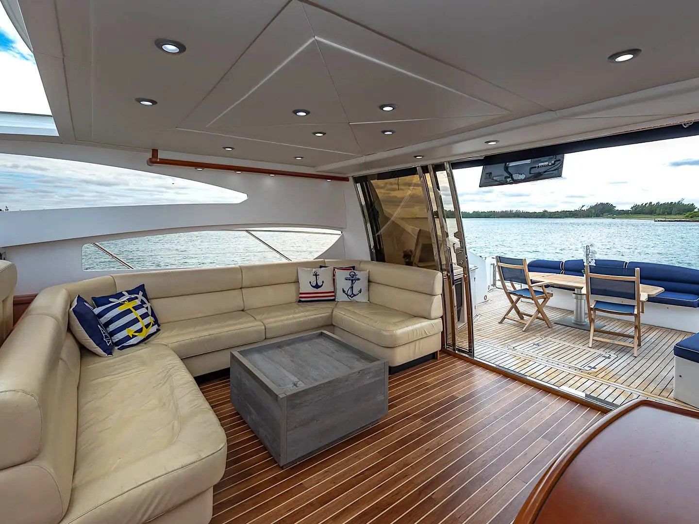 Luxurious yacht interior with leather seating and outdoor deck view over water.