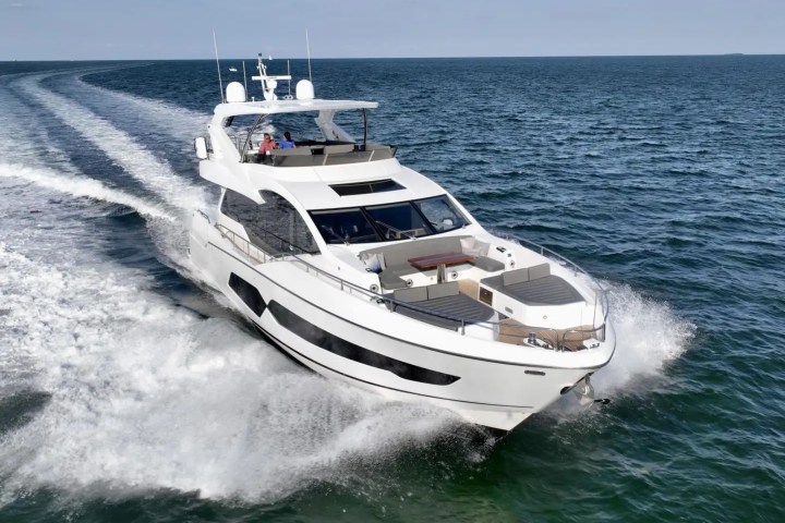 A white yacht cruising on the ocean, creating waves behind it on a sunny day.