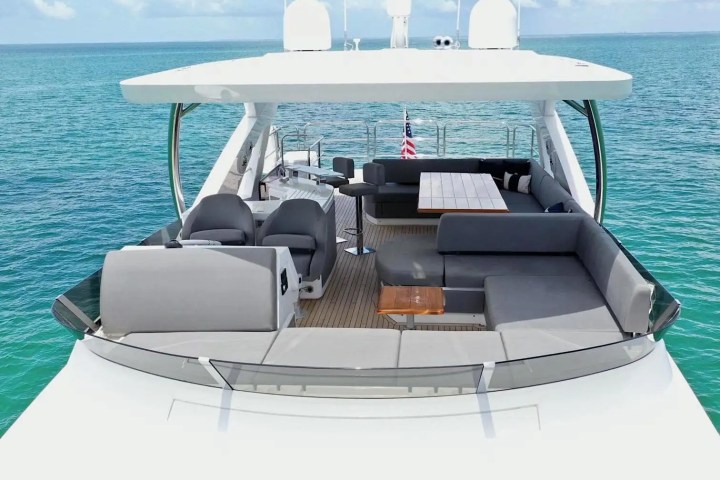 Luxurious yacht deck with grey seating, table, and ocean view.