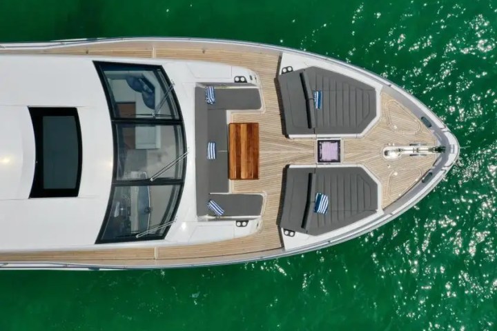 Aerial view of a yacht deck with seating and sunbeds on calm green water.