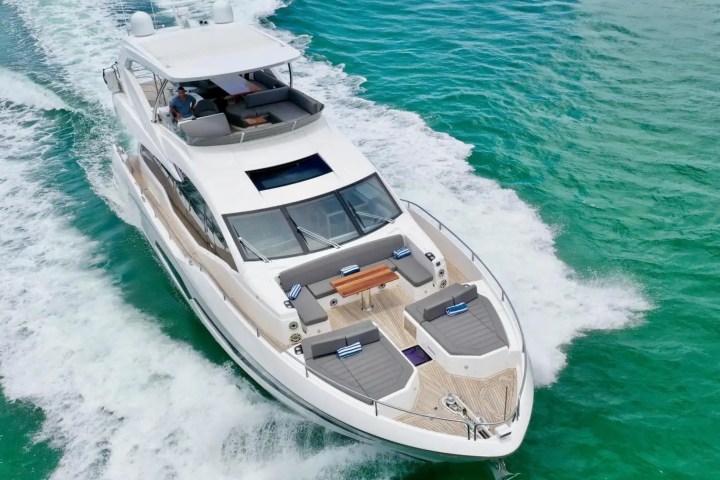 White yacht cruising on clear turquoise water with visible wake behind.