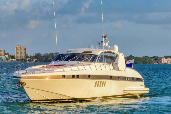 Luxury yacht on water near city buildings under a partly cloudy sky.