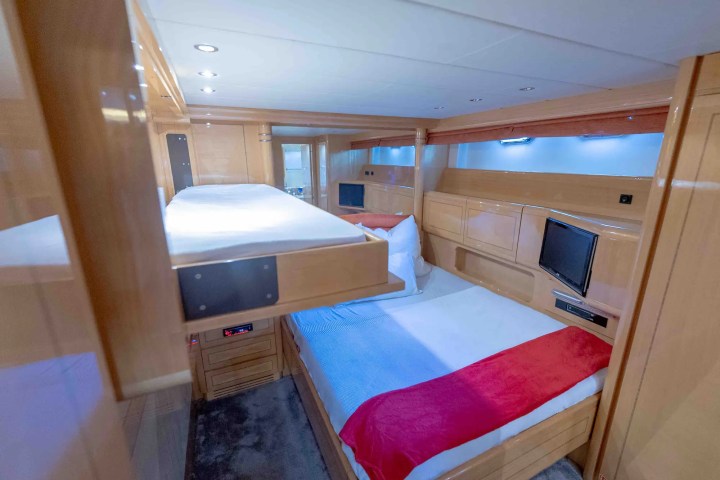 Cozy cabin room with a double bed, bunk bed, wooden walls, and a mounted TV.