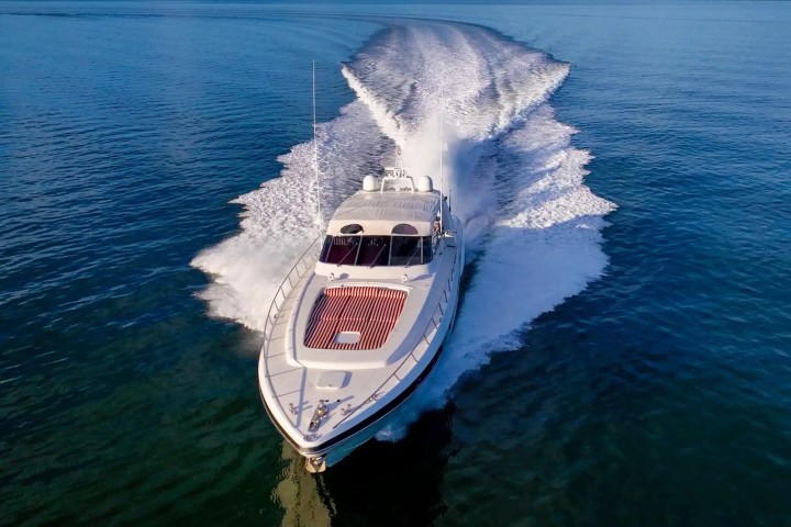 Speedboat cruising on blue ocean, creating white foamy waves.