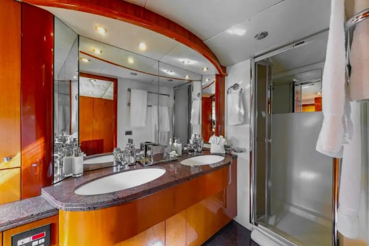 Luxurious yacht bathroom with double sinks, large mirror, and a glass shower enclosure.