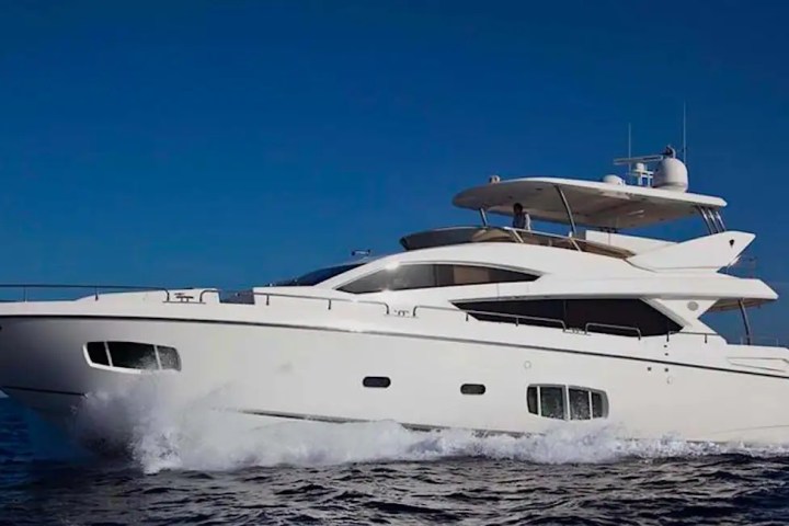 White yacht cruising on the ocean with a clear blue sky in the background.