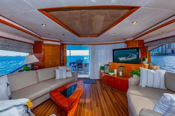 Luxurious yacht interior with sofas, TV, and ocean view through large windows.