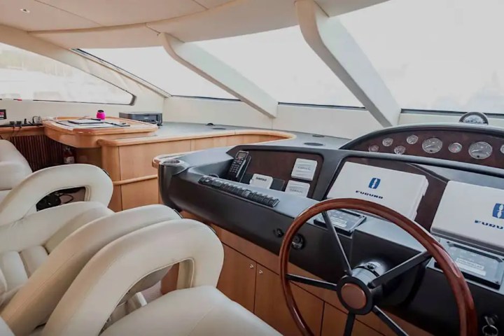 Interior of a yacht cockpit with leather seats, steering wheel, and control panels.