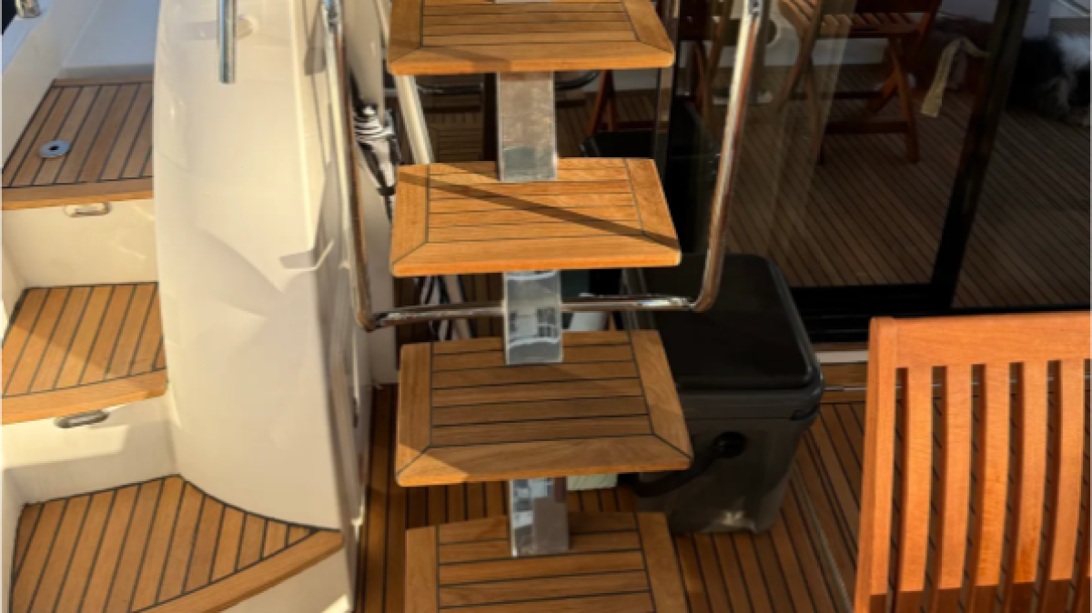 Wooden steps and railing on a boat deck with a table and chairs.