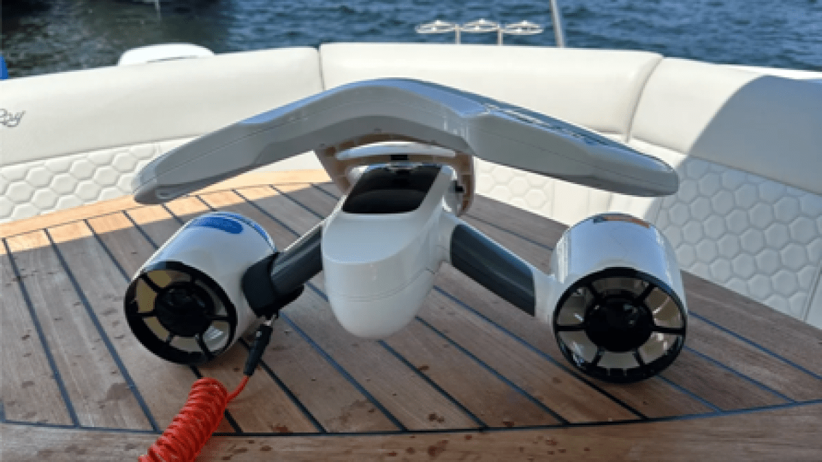 An underwater scooter on a boat's table with an American flag and a marina in the background.