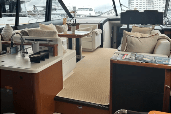 Luxurious yacht interior with sofas, dining area, and panoramic windows.