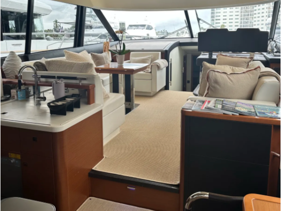 Luxurious yacht interior with sofas, dining area, and panoramic windows.