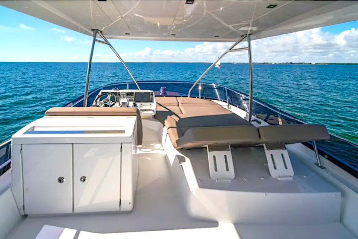 View of a yacht's deck with seating, overlooking a calm ocean under a blue sky.