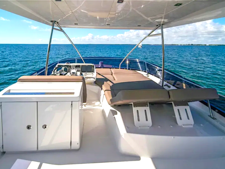 View of a yacht's deck with seating, overlooking a calm ocean under a blue sky.