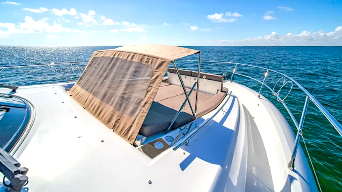 Boat deck with tan sunshade, ocean view, and blue sky with clouds.