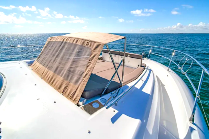 Boat deck with tan sunshade, ocean view, and blue sky with clouds.