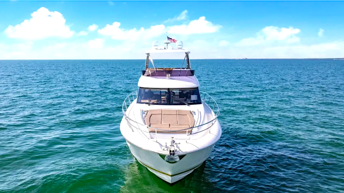 White yacht on open water with clear blue sky and scattered clouds.
