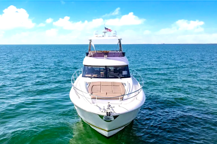 White yacht on open water with clear blue sky and scattered clouds.