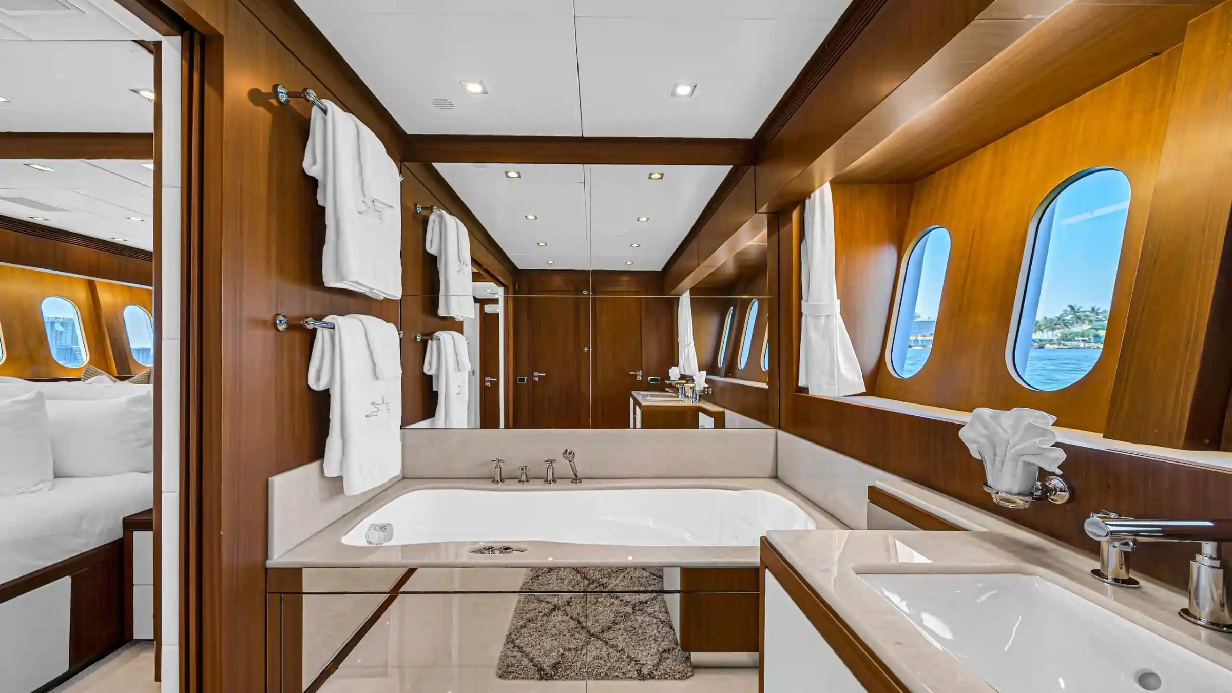 Luxurious yacht bathroom with wooden decor, bathtub, and windows overlooking the sea.