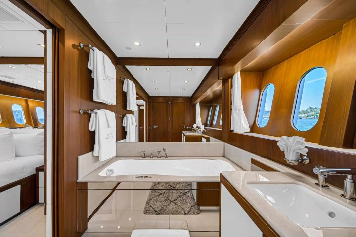 Luxurious yacht bathroom with wooden decor, bathtub, and windows overlooking the sea.
