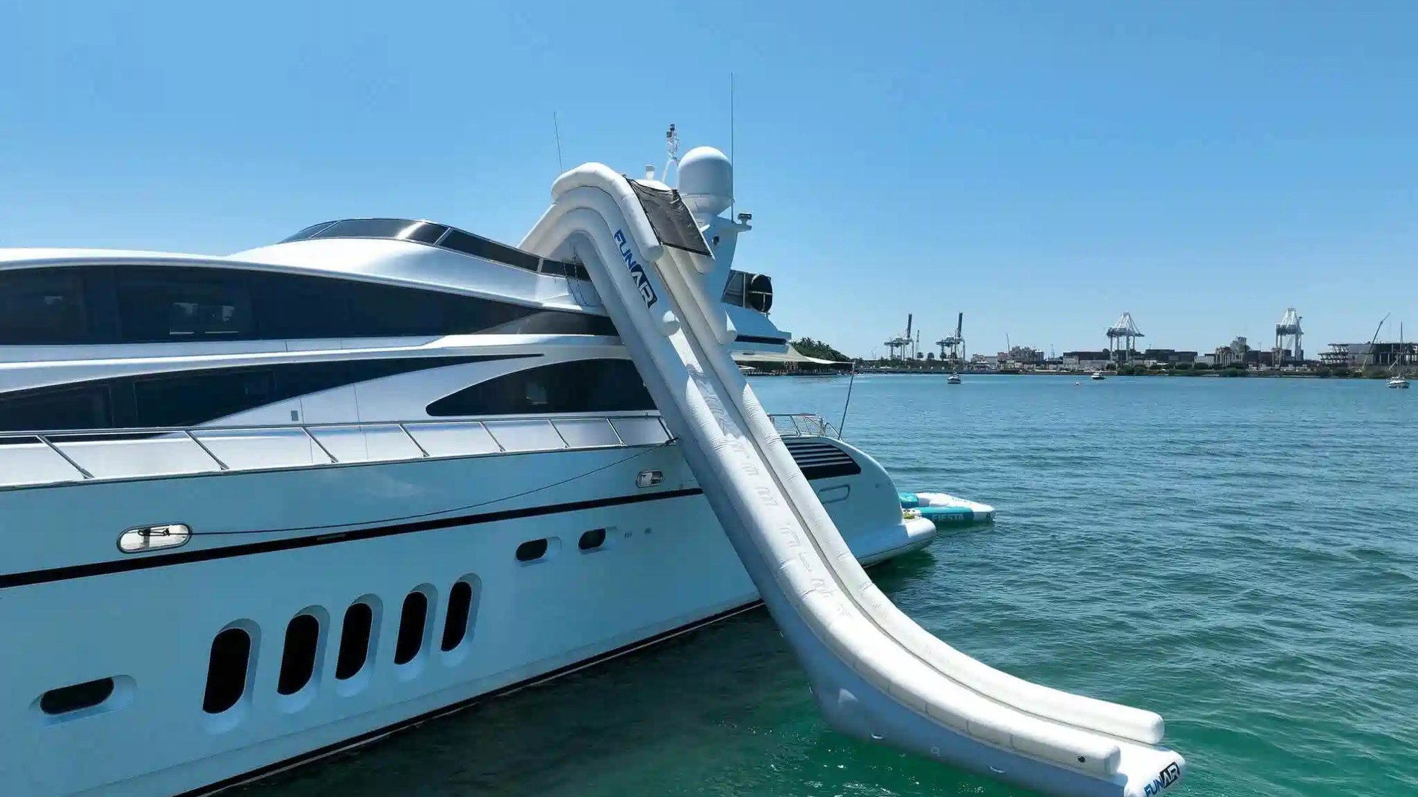 Luxury yacht with an inflatable slide leading into the ocean on a clear day.
