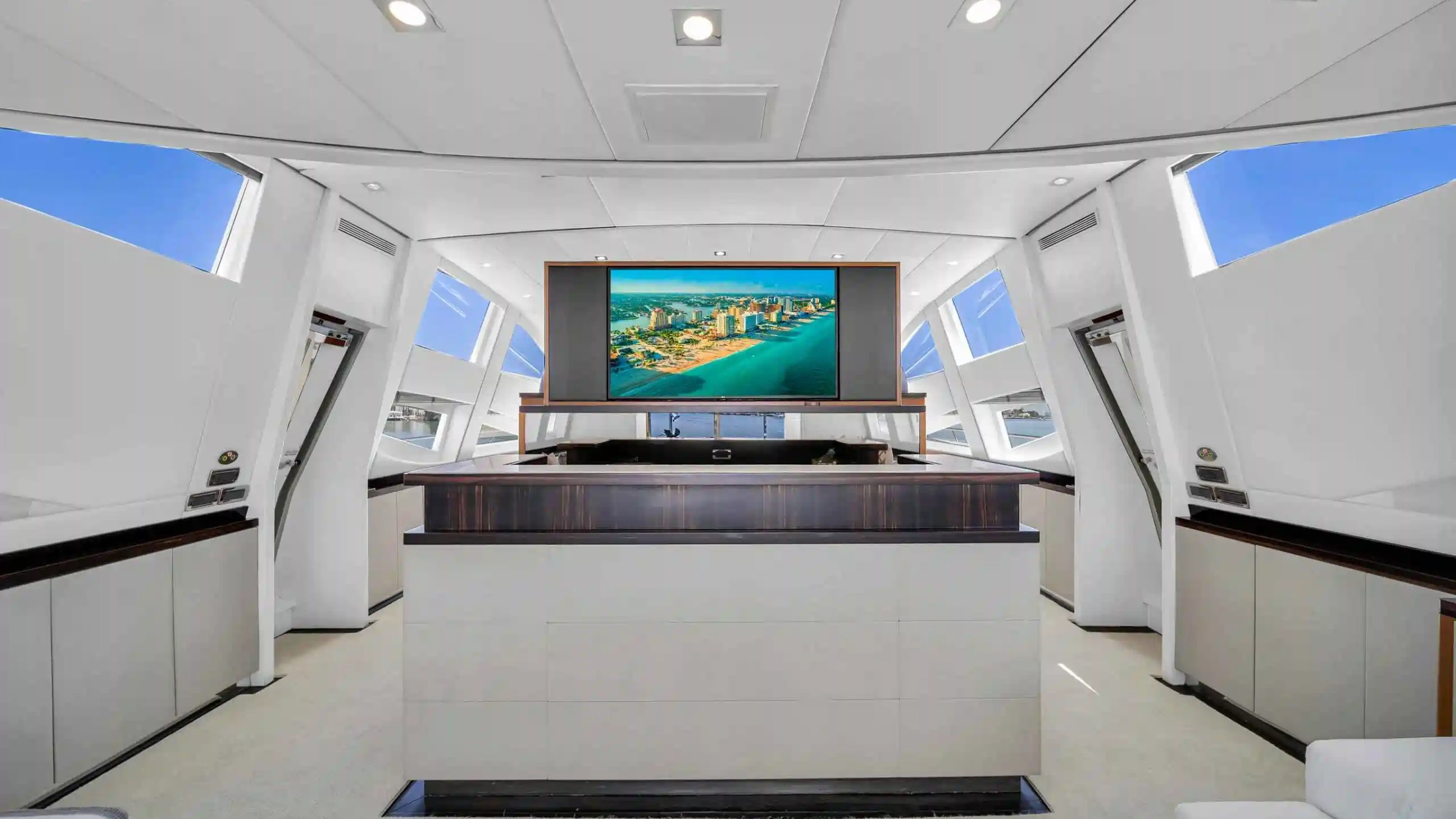 Modern yacht interior with large TV displaying a cityscape, white walls, and sleek design elements.
